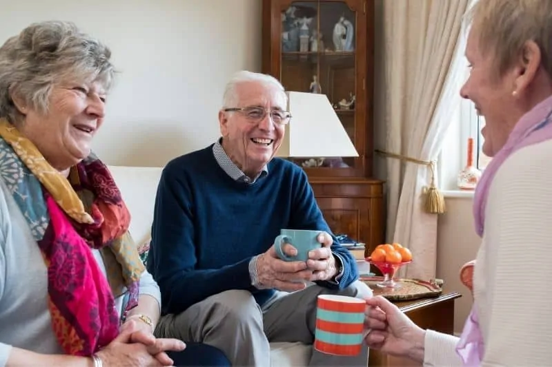 3 personnes autour d'un café discutent joyeusement