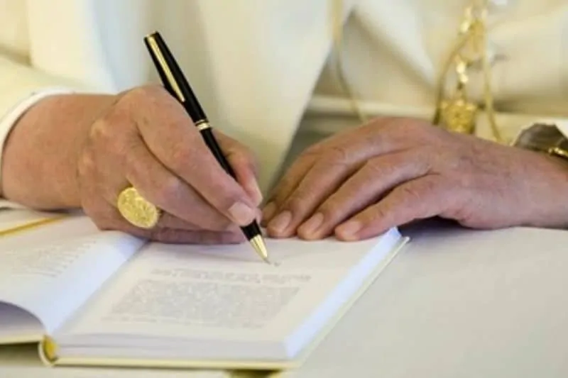 les mains du Pape qui écrit son encyclique