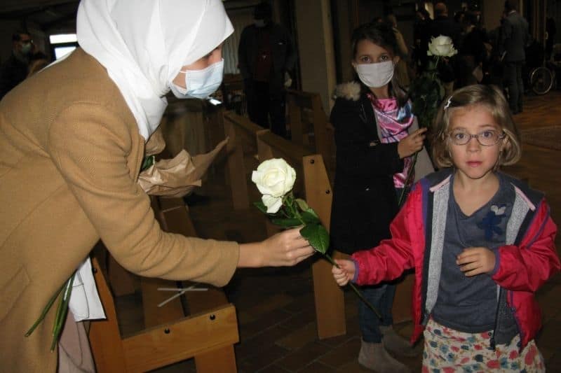 une femme musulmane remet une rose blanche à une une petite fille chrétienne