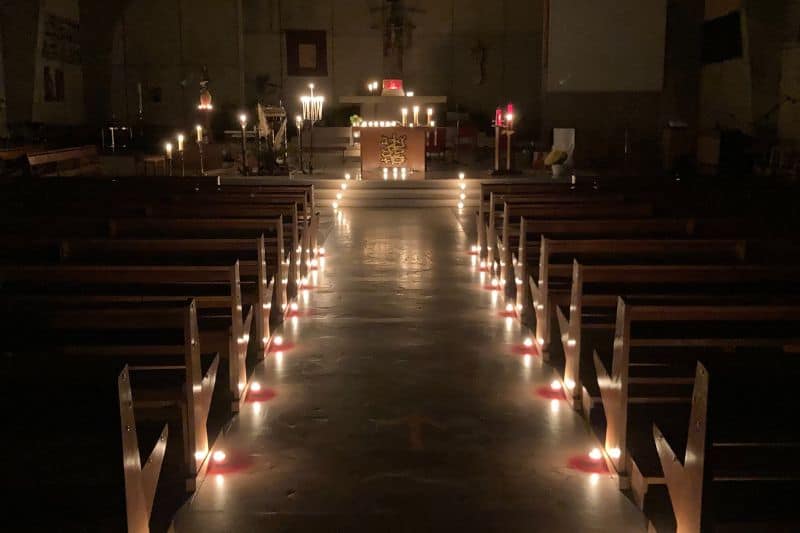 Eglise Saint-Aldric dans la pénombre éclairée par des lumignons posées au sol à la bordure des bancs