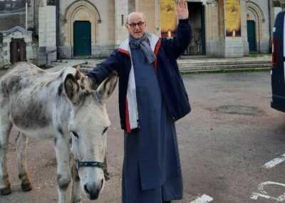 Père Marie-Benoit saluant avec un âne sur la parvis de Notre-Dame du Chêne