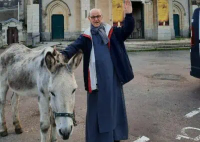 Père Marie-Benoit saluant avec un âne sur la parvis de Notre-Dame du Chêne