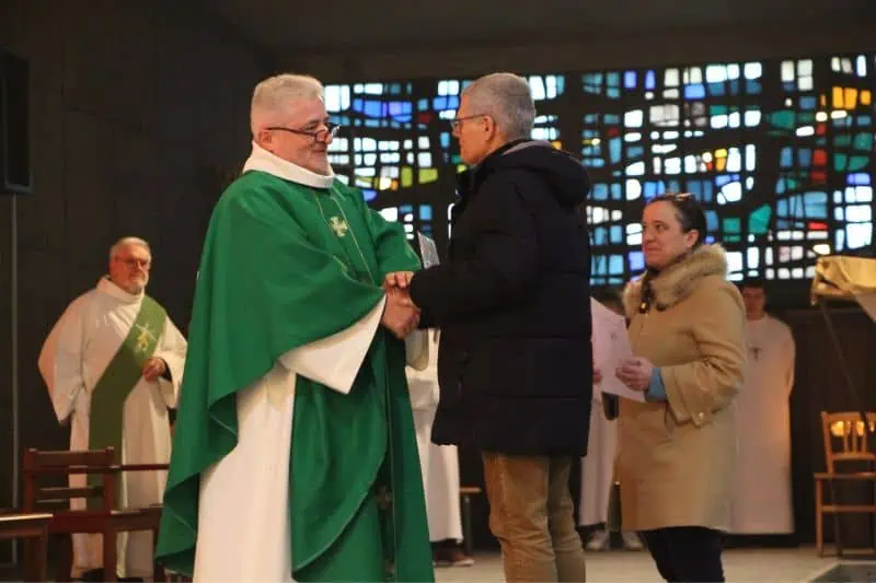 Le père Cador remet à deux baptisés des lettres de mission à l'église Saint-Liboire