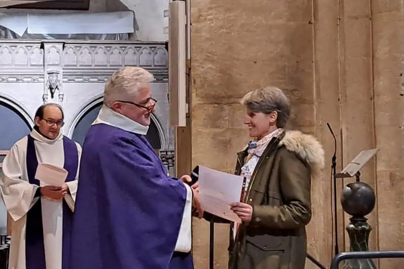 Le père Cador dans une chasuble violette remet à Anne-Laure Restout une lettre de mission à Notre Dame de La Couture