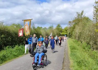 Une personne en fauteuil ouvre la marche d'un chapitre de pélerins